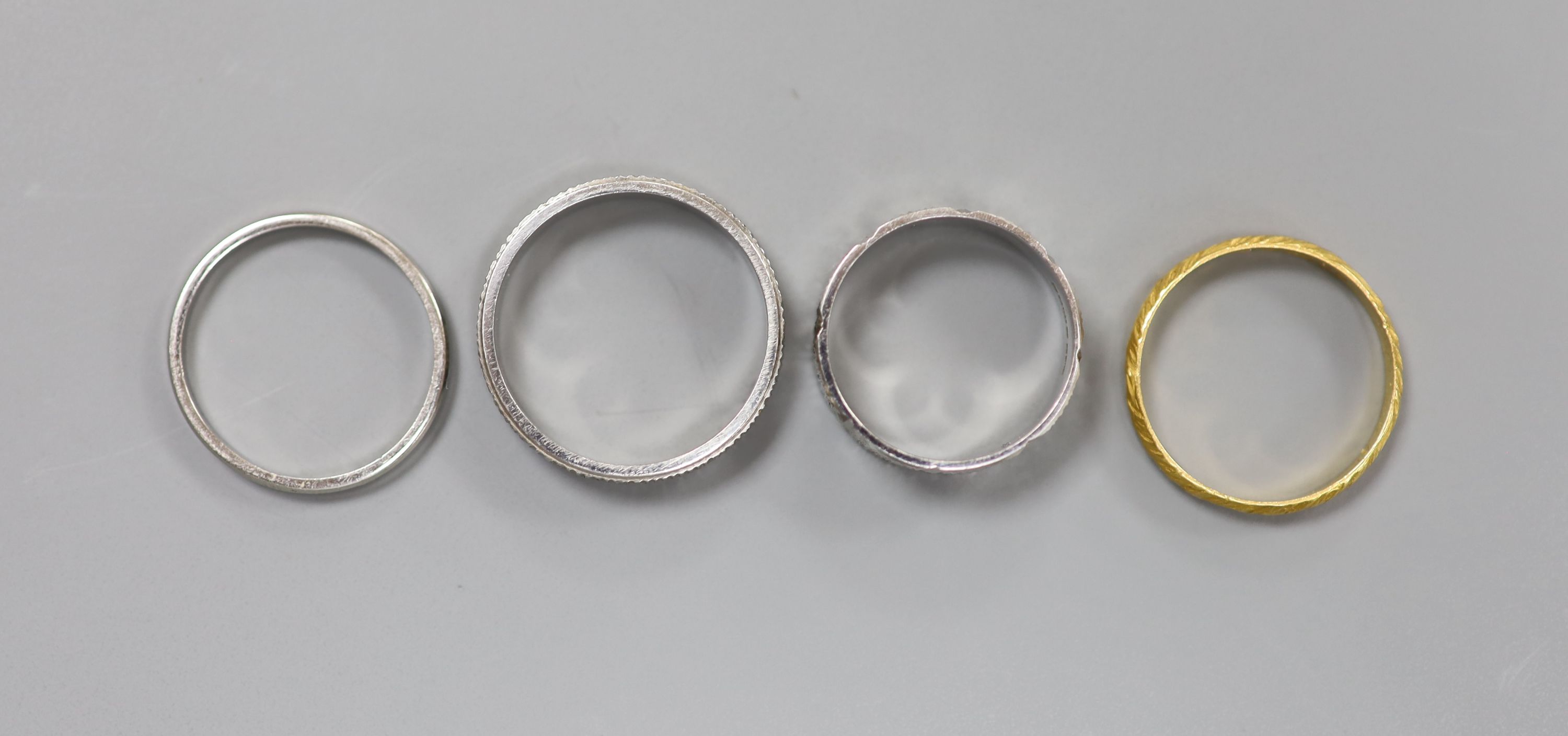 Two platinum wedding bands, 7.8 grams, an 18ct white gold wedding band, 3.7 grams and a 22ct gold band, 1.8 grams.